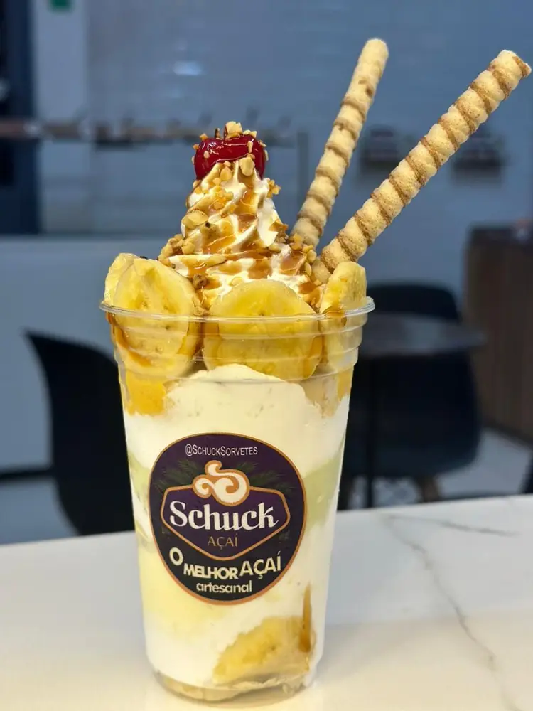 Banana split no copo com calda de caramelo e canudos de biscoito