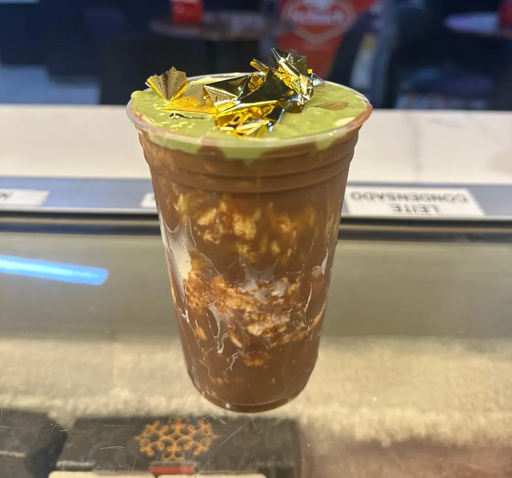 Copo de sorvete de chocolate com creme de pistache e folha dourada por cima