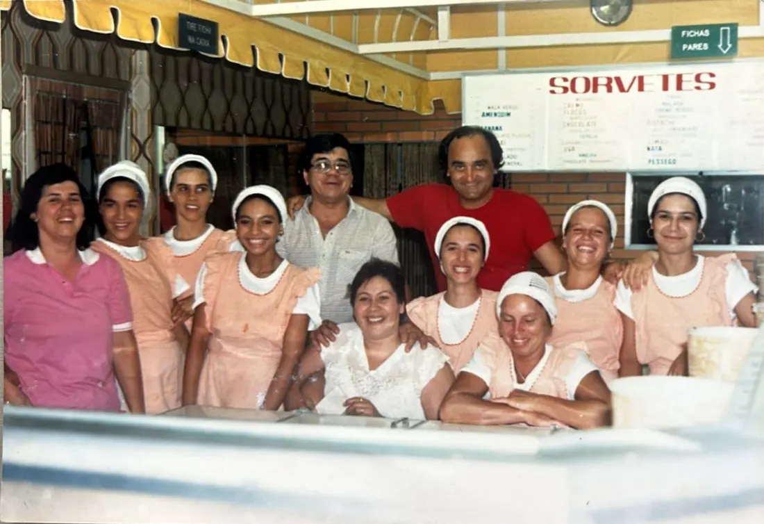 Foto antiga: equipe da Schuck de uniforme e touca, reunida atrás do balcão de sorvetes