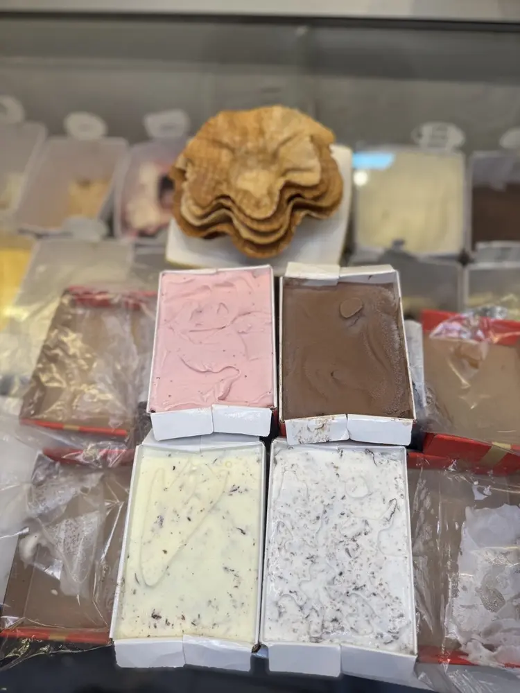 Cascões artesanais empilhados atrás de caixas de sorvete abertas, de morango, chocolate e flocos