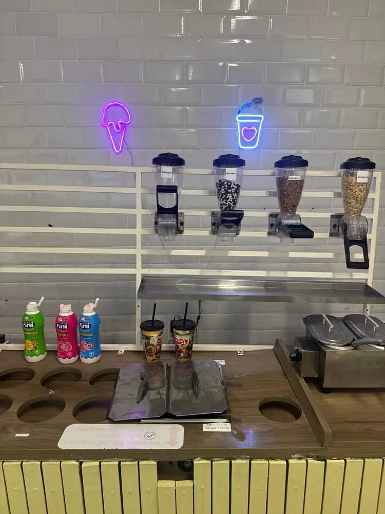 Bancada de coberturas do buffet com letreiros de neon de sorvete e copo