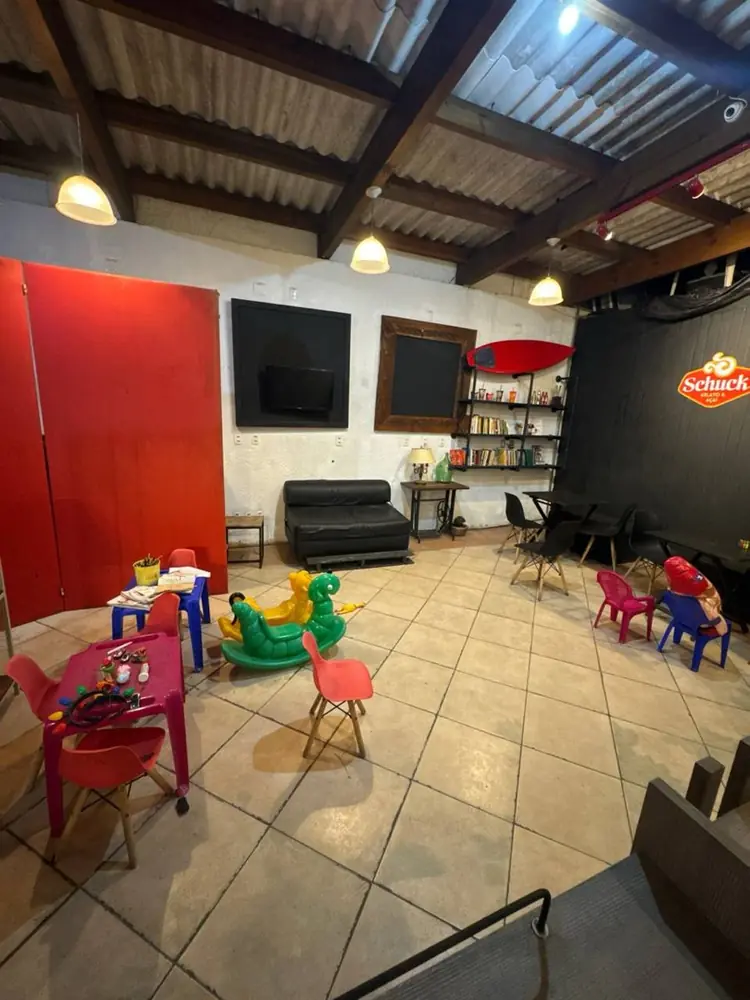 Sala ao lado com espaço kids, mesinhas coloridas, gangorras e sofá