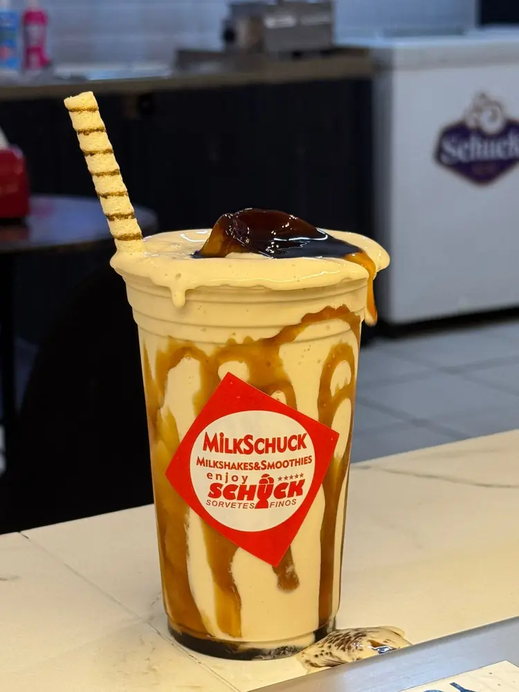 Milkshake com calda de caramelo escorrendo pelo copo e canudo de biscoito